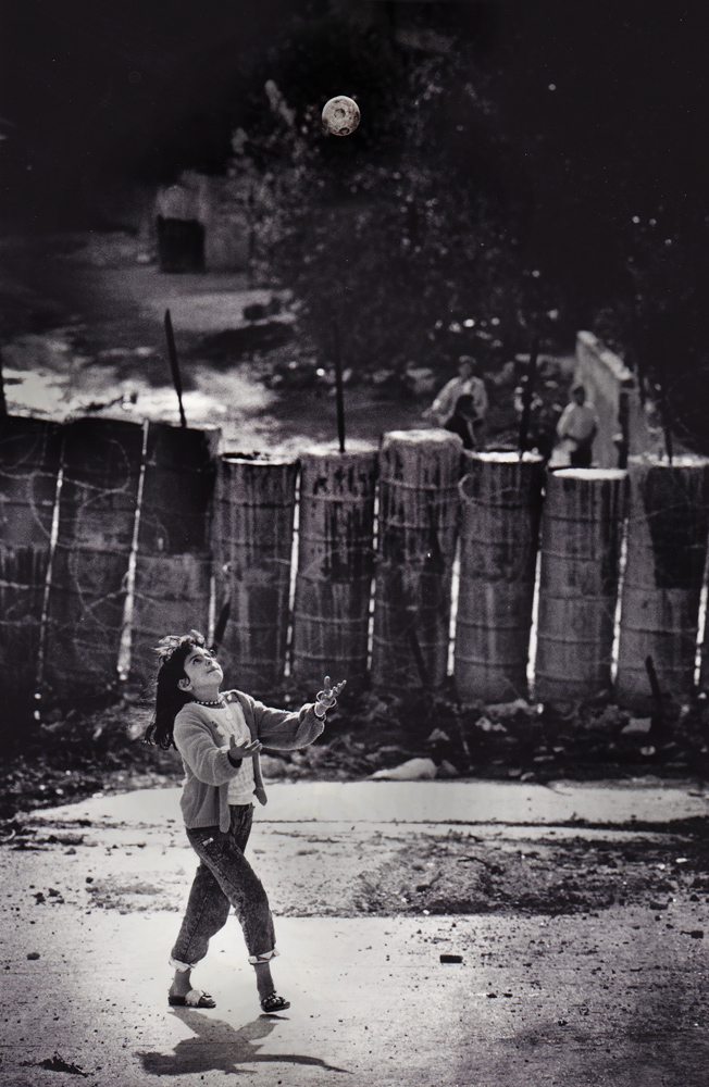 Palestinian Girl plays ball with backdrop of Israeli barricade : Jenin : West Bank